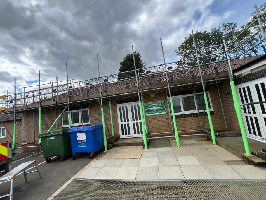 Building undergoing renovation with scaffolding and construction bins outside.